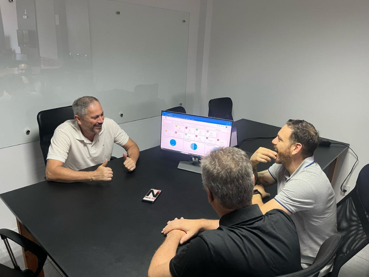 Empreendedores de pequenas empresas discutindo a implementação de IA em um ambiente de escritório profissional, com painéis de dados exibidos na tela